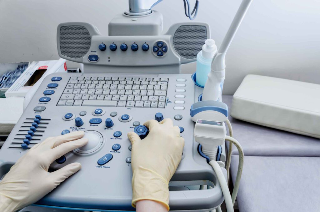 Person mit Gummihandschuhen bedient Ultraschallgerät.